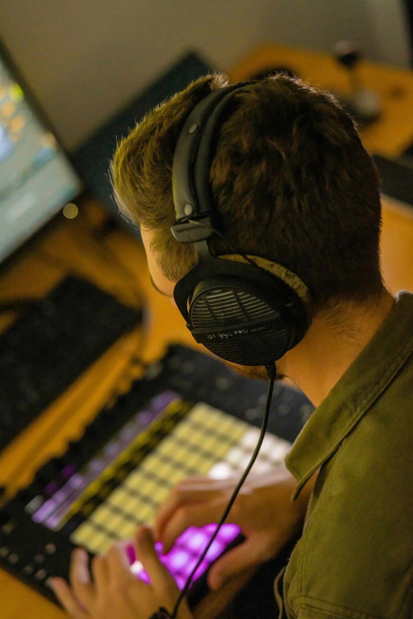  Image of a man using headphones and a music production device at Production Music Tools (PMT). Keywords: PMT, Production Music Tools, headphones, music production.