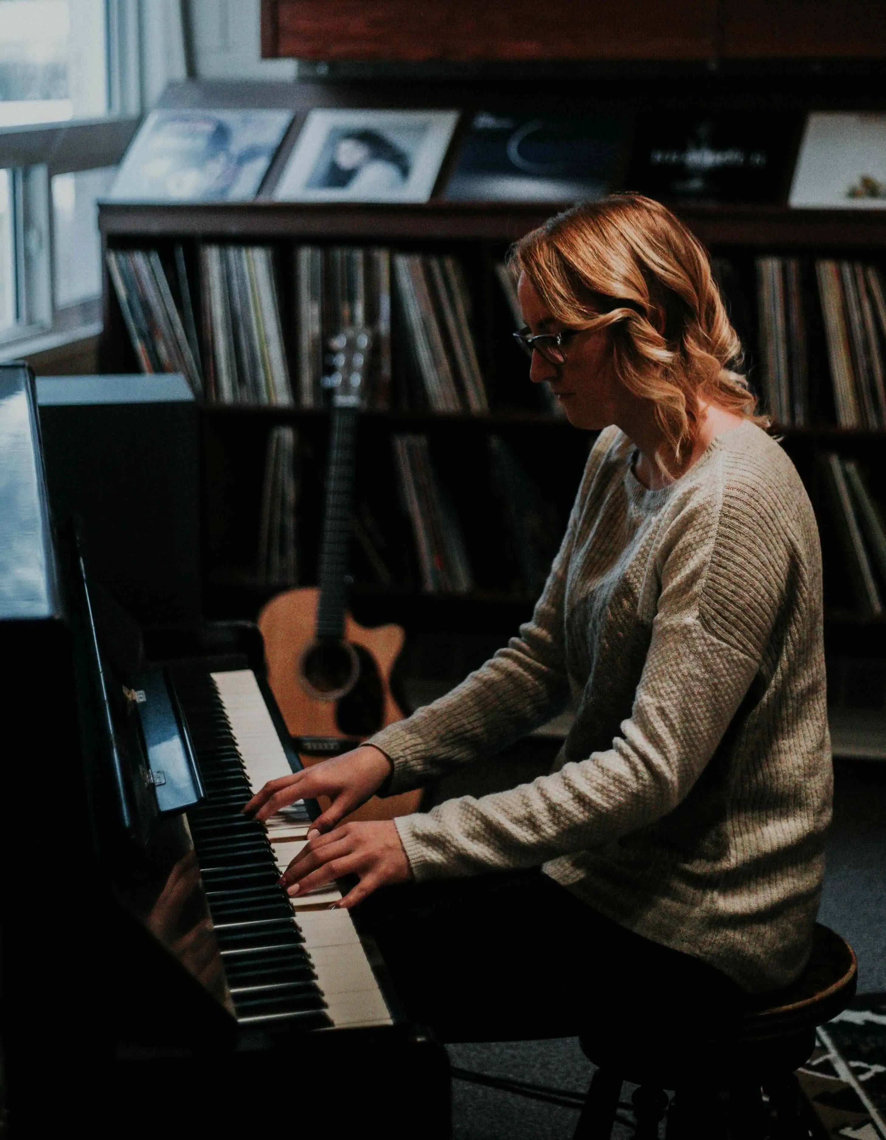 A banner image for Production Music Tools featuring a woman playing the piano, leading to the About Us section via a clickable button. The visible text on the image reads: 'Empowering Music Producers Globally. We believe in setting music producers up with the tools to succeed in a competitive landscape. About Us.